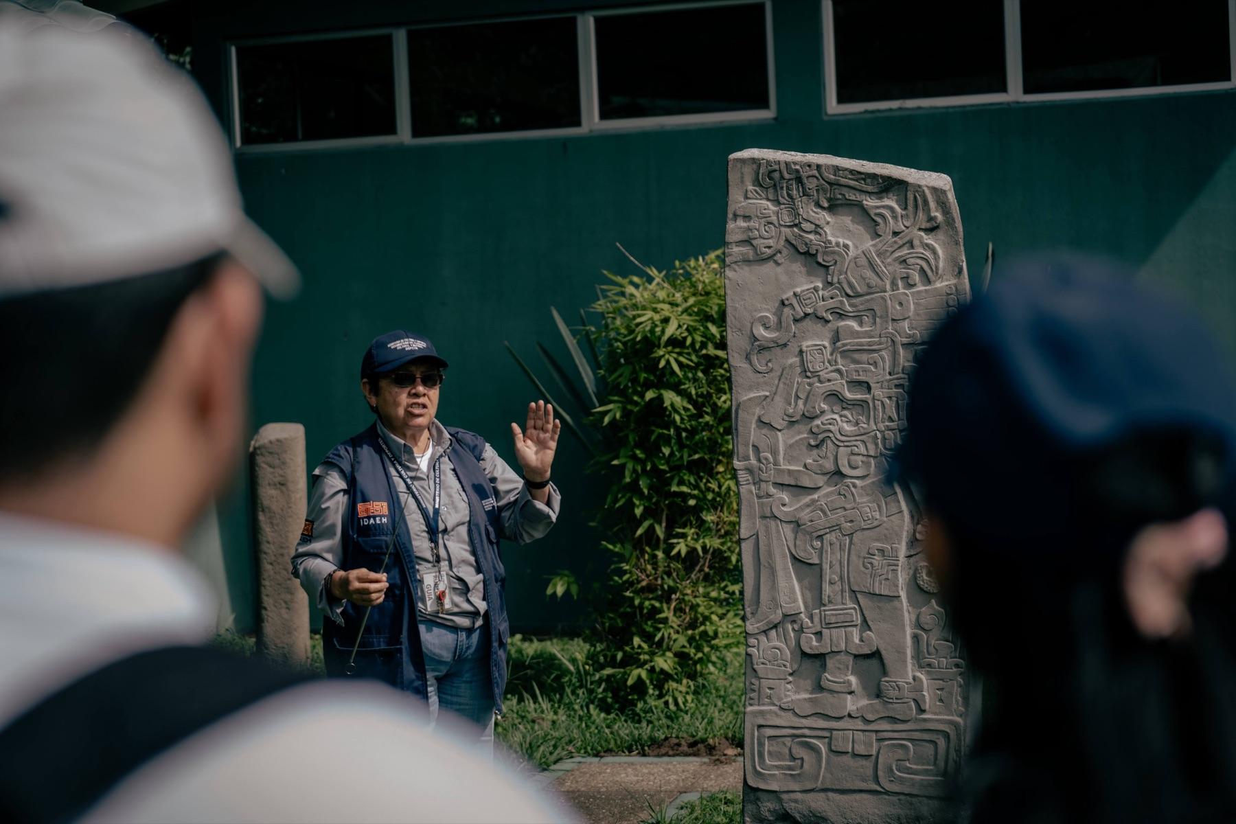 Guía explicando frente a una estela maya